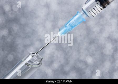 A syringe draws a vaccine from a medical bottle. On gray Stock Photo