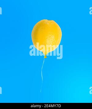 Lemon balloon isolated on blue background, funny tropical fruit concept Stock Photo