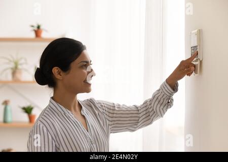 Happy millennial indian female homeowner managing smart house electronic system Stock Photo