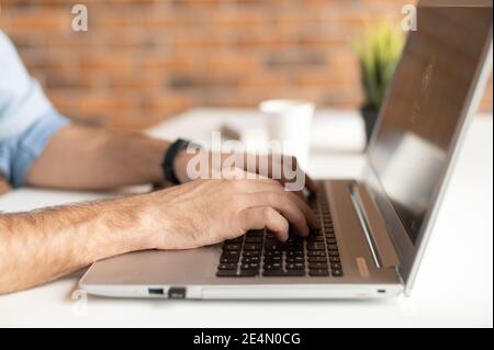 A male hands typing on the keyboard, unrecognizable face. Freelance developing software, a journalist is writing an article, chatting in a networks Stock Photo
