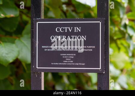 'CCTV in operation' sign on the gates to St Johns College, Oxford, Oxfordshire, UK Stock Photo