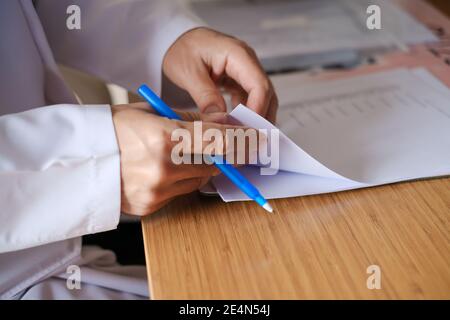 The doctor examines the patient's documents. Side  view of doctor hand writing prescription on paper. Health and medical concept. Stock Photo