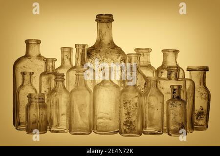 A collection of old antique bottles with a sepia tone. There are 18 ancient bottles, and they are dirty. Focus on the front row. Stock Photo