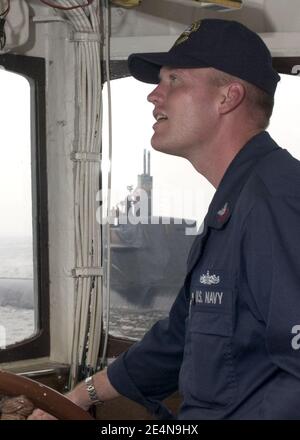 US Navy Boatswain's Mate 1st Class maneuvers the tugboat USS Opelika (YTB 798) as it approaches the Los Angeles-class fast attack submarine USS Buffalo (SSN 715). Stock Photo