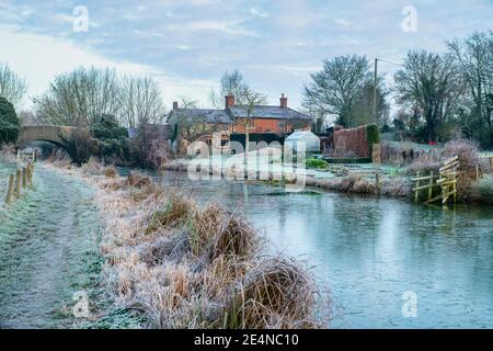 Canal bridge and cottage along the oxford canal in the january frost at sunrise. Somerton, Oxfordshire, England Stock Photo