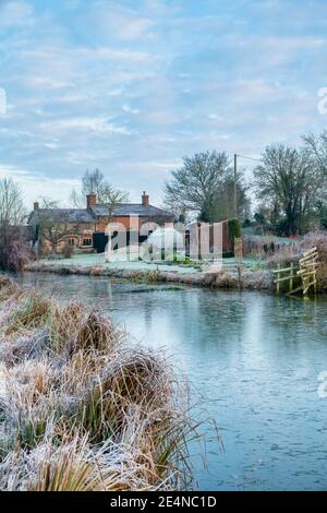 Canal bridge and cottage along the oxford canal in the january frost at sunrise. Somerton, Oxfordshire, England Stock Photo