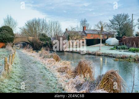 Canal bridge and cottage along the oxford canal in the january frost at sunrise. Somerton, Oxfordshire, England Stock Photo