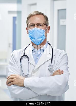 Confident old professional doctor wearing face mask looking at camera. Stock Photo