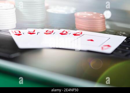 Online gaming platform, casino and gambling business. Cards, dice and multi-colored game pieces on laptop keyboard. Stock Photo