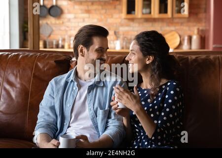 Happy couple relax on sofa drinking coffee talking Stock Photo