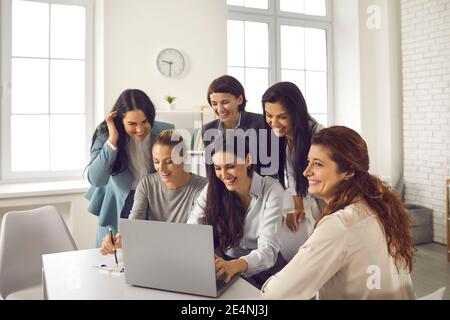 Team of happy young women using laptop while working on business project together Stock Photo