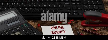 The concept of an online survey. The text is written on a white sheet of paper, which lies on the desktop next to the calculator and keyboard of the c Stock Photo