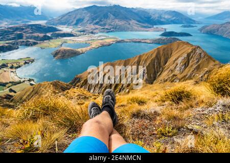 Adventure and hiking wanderlust travel vacation concept with hikers hiking boots close up. Hiker man looking at view from famous hike to Roys Peak on Stock Photo
