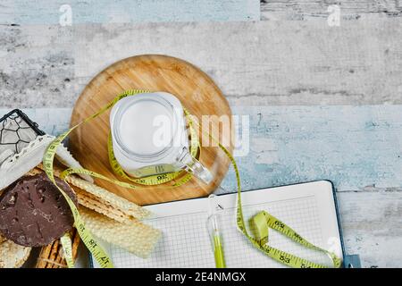 Basket of biscuits and a jar of milk on a marble table with a notebook Stock Photo