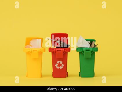 three multi-colored plastic containers on a yellow background, the concept of correct sorting of garbage for further recycling Stock Photo