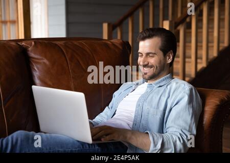 Smiling Caucasian man use computer talking on video call Stock Photo