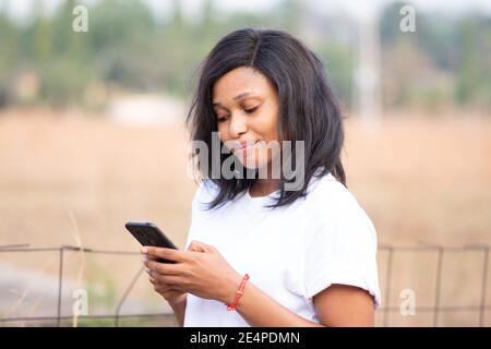 pretty light skin african lady using her phone outdoor, with blurred background Stock Photo