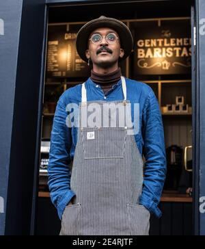 Male Barista cafe owner wearing apron outside coffee shop, food and drink business start up. Stock Photo