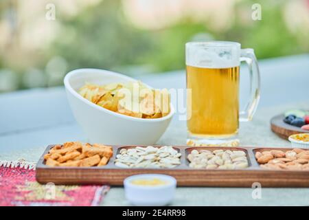 Assorted snacks, chips, and a glass of beer on stone table Stock Photo