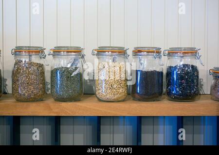 Rustic kitchen tea storage arrangement in glass jars with white wood background. Stock Photo