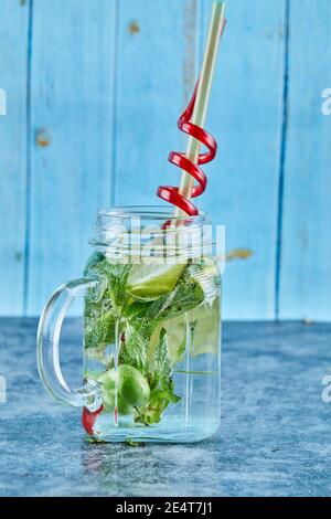 Mojito cocktail with slices of lime and mint on blue table Stock Photo