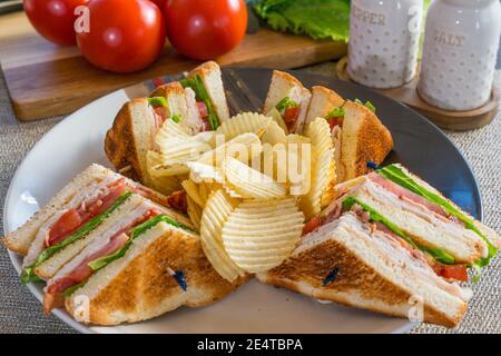 Fresh turkey club sandwich on white toast with potato chips on a plate Stock Photo