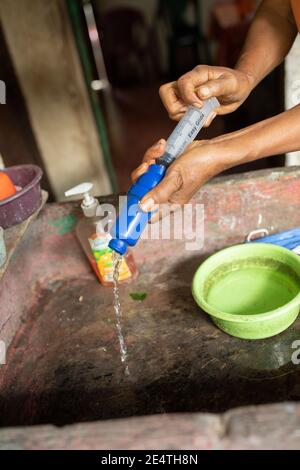 Backwash cleaning a home tap-based water filter system in use in San Juan la Laguna, Guatemala. Stock Photo