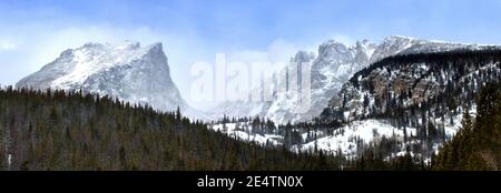 Panorama of Hallet Peak and Flattop as viewed from Rocky Mountain National Park as snow blows over the mountain peaks Stock Photo