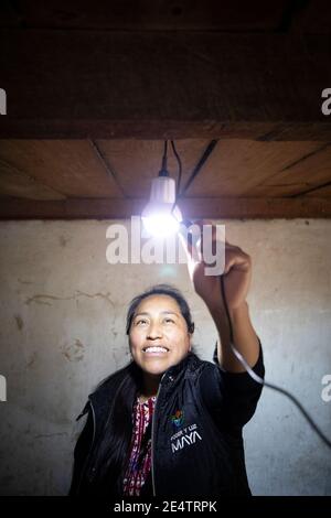 A technician from local non-profit power company test a new solar powered lighting system in a home in Cantel, Guatemala, Centr Stock Photo