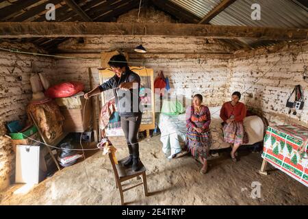 A technician from local non-profit power company installs a new solar powered lighting system in a home in Cantel, Guatemala. Stock Photo