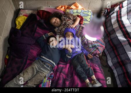 Children underneath a lit electric light bulb in their home Cantel, Guatemala, Central America.