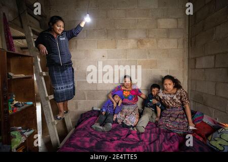 A technician from local non-profit power company tests a new solar powered lighting system in a home in Cantel, Guatemala, Central America.