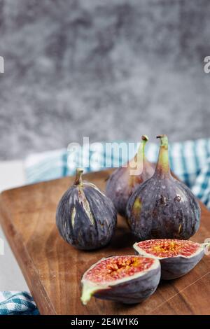 Half slices and whole figs on a wooden board with a blue tablecloth Stock Photo