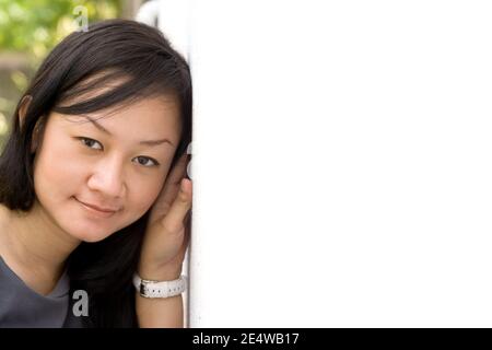 Closeup portrait of pretty Asian young woman leaning her head on a white wall Stock Photo