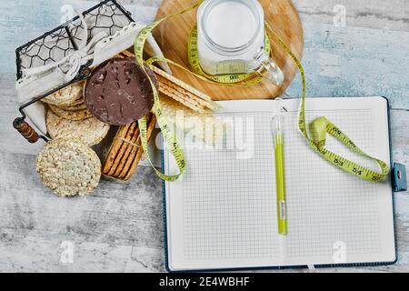 Basket of biscuits and a jar of milk on a marble table with a notebook and pen Stock Photo