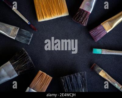 Close-up various used artist paint brushes many size arrange in circle isolated on dark background with copy space. Stock Photo
