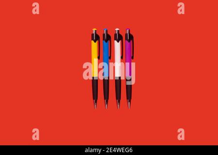four colored pens lying on a red background Stock Photo