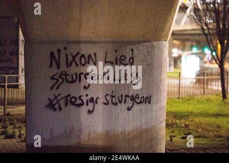 Glasgow, Scotland, UK. 25th Jan, 2021. Pictured: Glasgow political graffiti artist known only as, ‘Clydebanksy' taking inspiration from the name Banksy the artist, is seen spray painting a slogan onto one of the pillars of the Kingston Bridge which reads, “NIXON LIED SSTURGEON LIESS #RESIGN STURGEON”. He has painted in the Schutzstaffel AKA the double ‘SS' in the words ‘Sturgeon' and the word ‘Lies' to make a point about how he feels the SNP are running the country. Credit: Colin Fisher/Alamy Live News Stock Photo