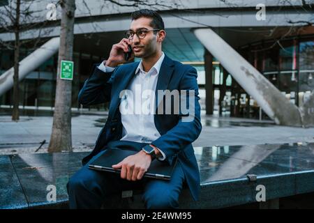 Mixed race businessman talking on cellular device taking break after long day at work  Stock Photo