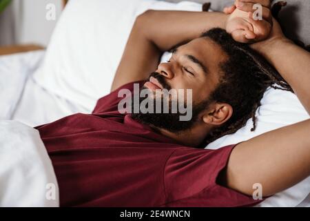 Tired young african-american man sleeping in bed Stock Photo