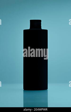 close up of a black unbranded bottle on tile blue background. cosmetic mock up. branding identity mockup concept. Stock Photo