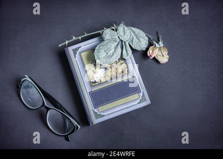 Book, dried rose flower with leaves and glasses Stock Photo