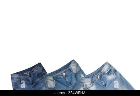 Waist and front pockets of three pairs of blue jeans slightly tilted on white background. Jeans have faded white spots and holes in them. Isolated. Co Stock Photo