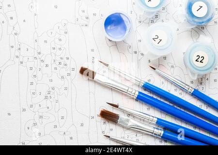 The artist's brush and multi-colored paint for painting on the coloring by numbers top view of the table Stock Photo