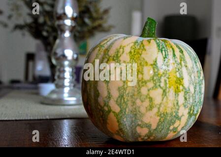 Pumpkin Sitting on Brown Wooden Table with Candle Holder Table Setting in Background Stock Photo
