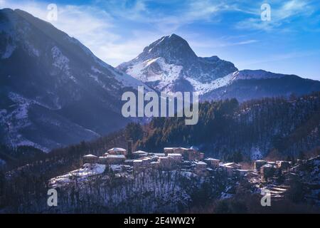 Snowy village and Apuan Alps mountains in winter. Nicciano, Garfagnana, Tuscany, Italy, Europe Stock Photo