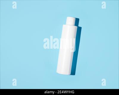 Empty white plastic bottle mockup in hard light. Top view or flat lay. Blank opaque bottle without packaging on blue background. Mock up for package design Stock Photo