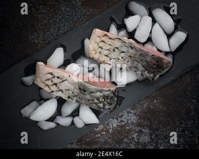 Raw carp fillets on black tray with ice. Overhead shot with copy space. Stock Photo