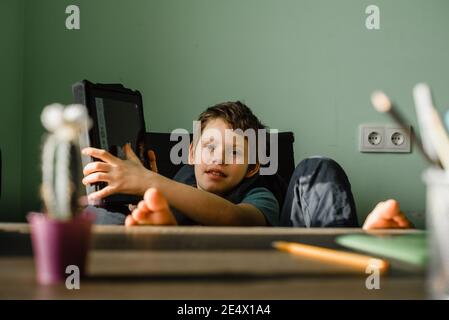 Smiling boy using tablet at home, growing up with technology Stock Photo