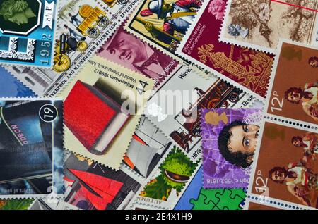 A jumbled mixture of past British commemorative postage stamps which people may collect or use to send letters and parcels through the Royal Mail Stock Photo